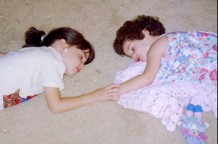 Young sisters fast asleep holding hands